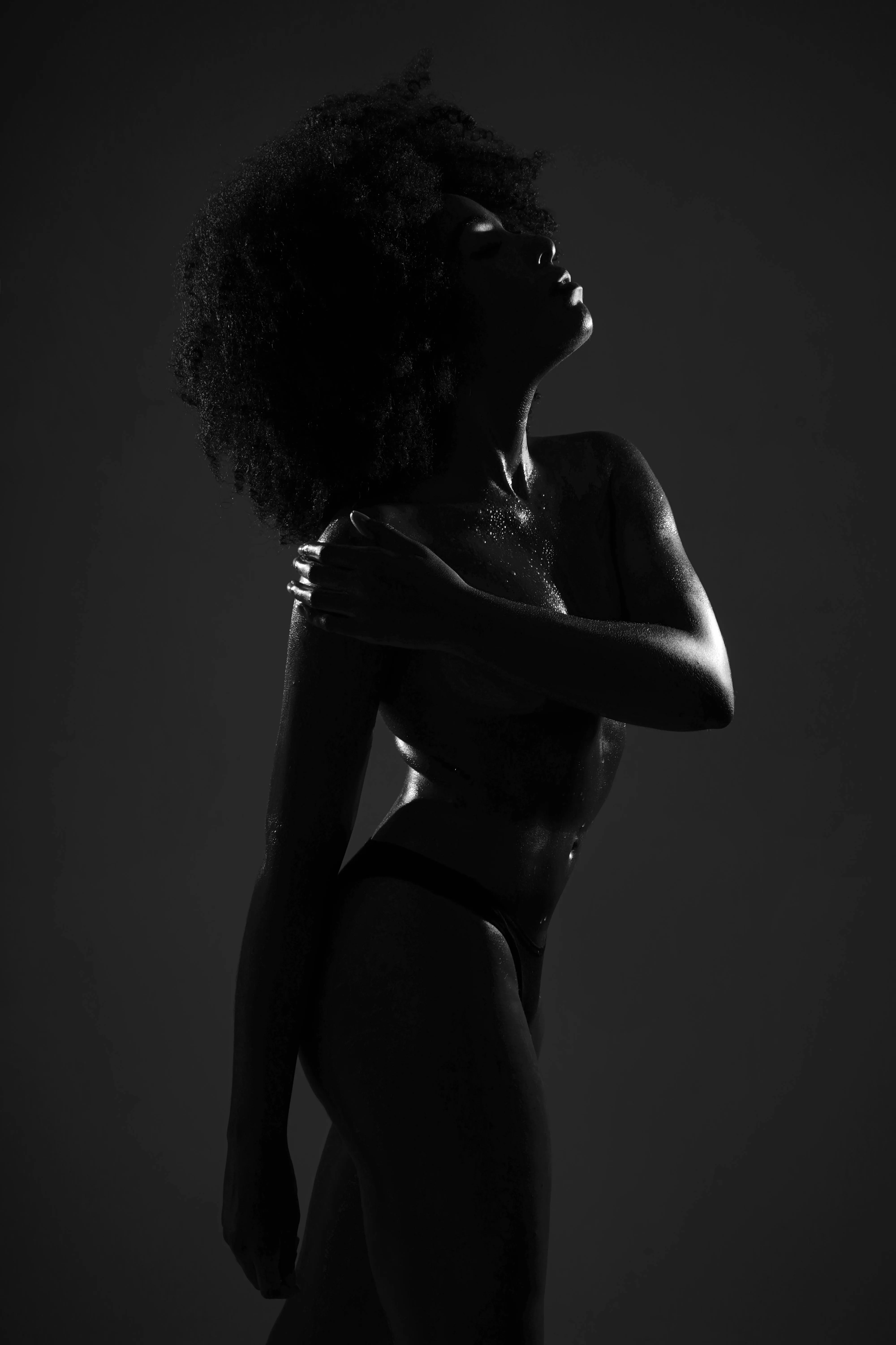 Silhouetted Woman in Dramatic Lighting Posing in Black Room