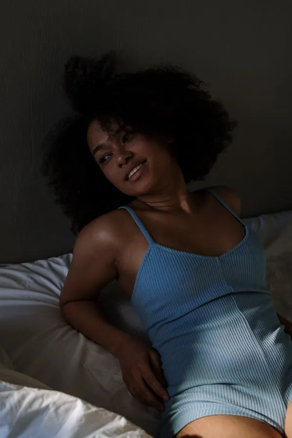 Smiling Woman with a Curly Hair Lounging in a Blue Dress