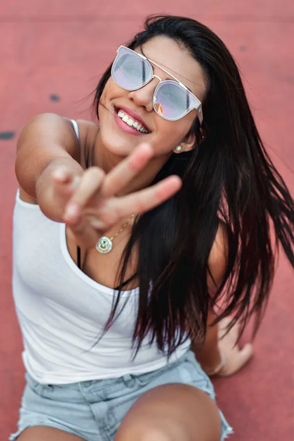 Smiling Woman in Sunglasses Wearing a White Top and Shorts