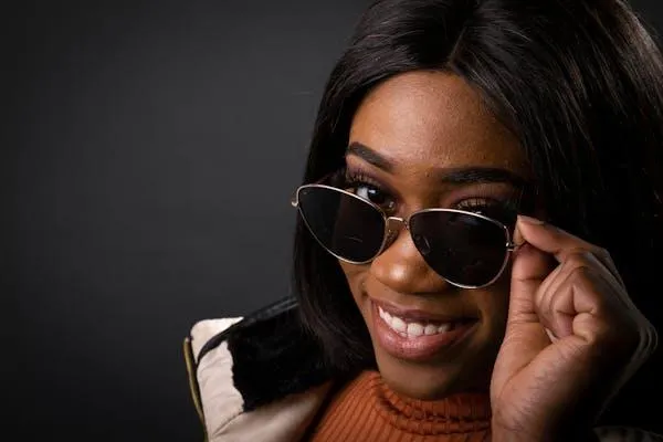 Smiling Woman Wearing Sunglasses Against a Black Background