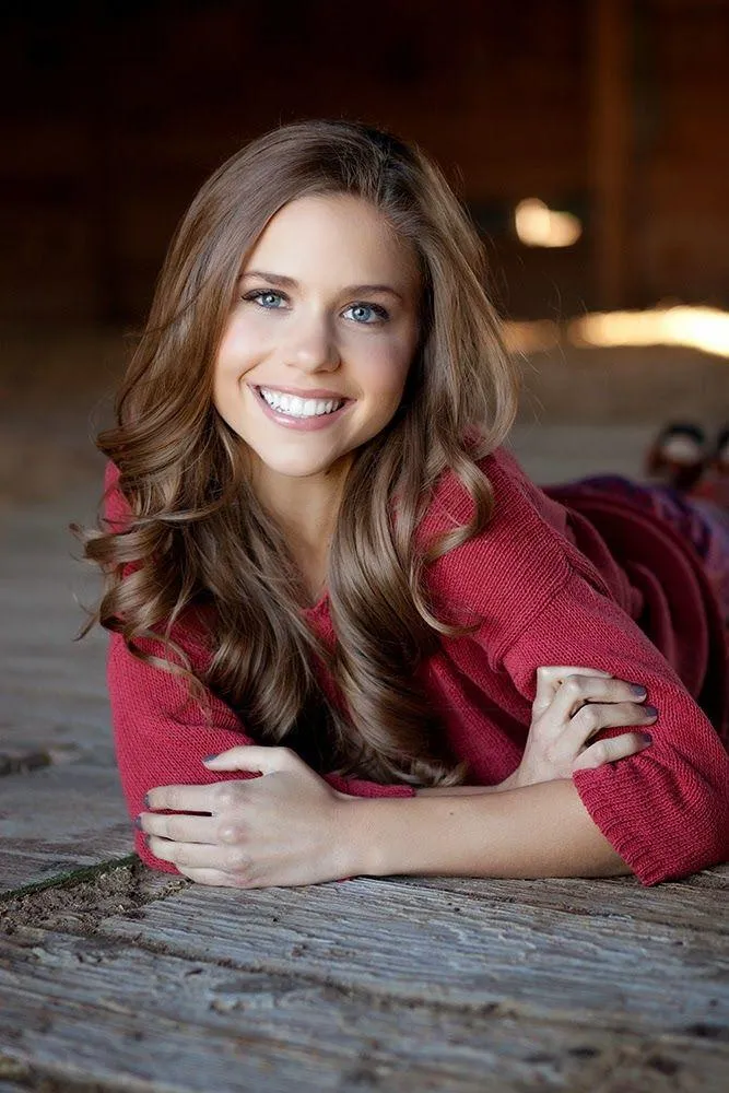 Smiling Young Woman Leaning on a Wooden Table Indoors Image