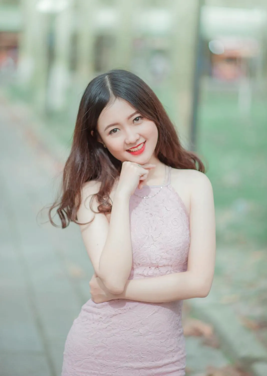 Smiling Young Woman in a Pink Dress Posing Playfully Outside