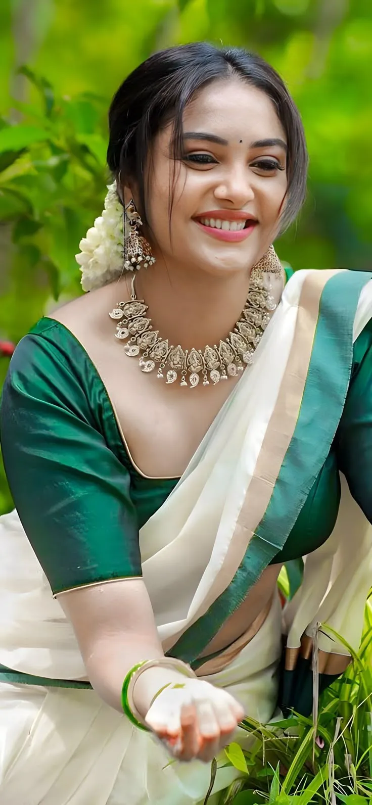 Smruthi Venkat in a Kerala saree sitting in a grassy field