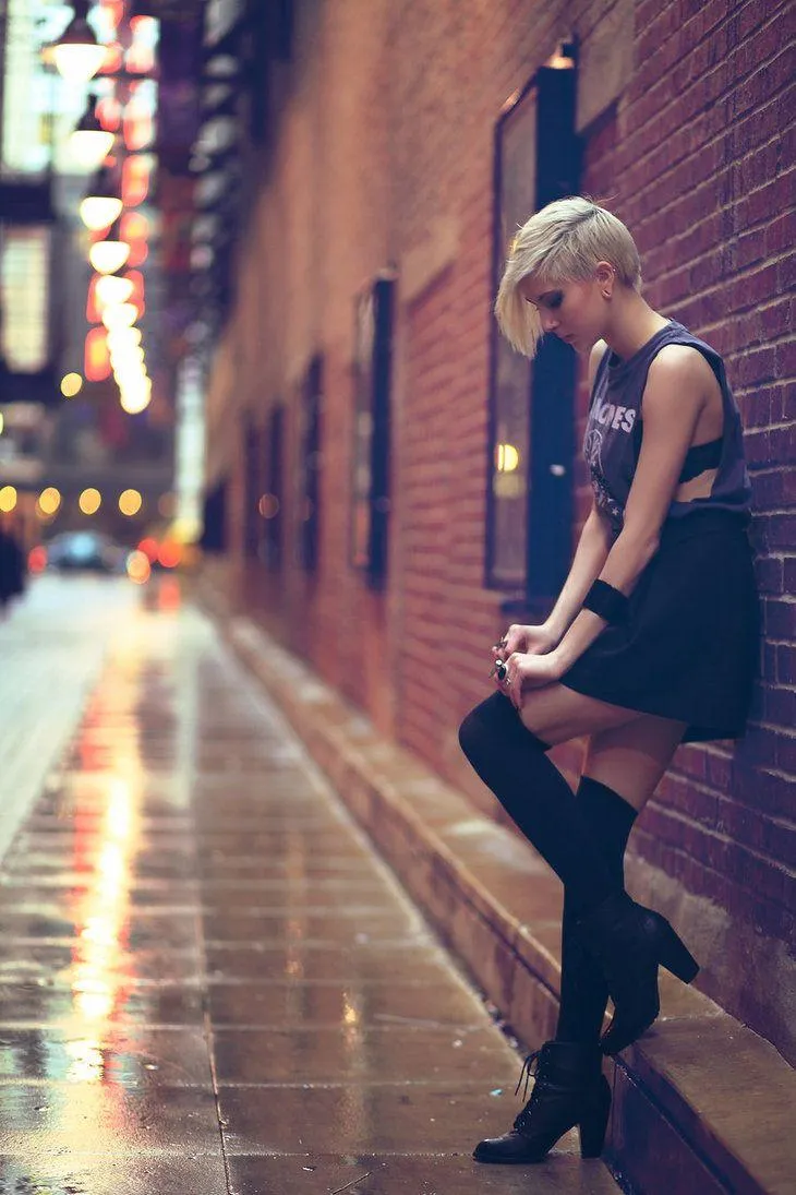 Stylish Girl Sitting in Alleyway Under Urban Evening Lights