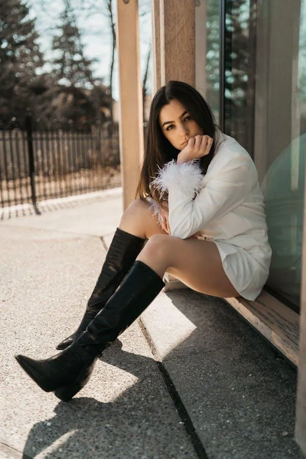 Stylish Woman with Boots Sitting Near a Glass Building