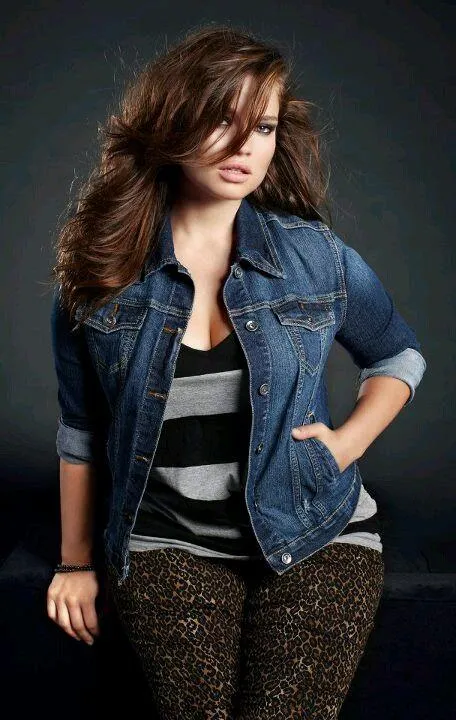 Stylish Woman in a Denim Jacket Standing Against a Dark Wall