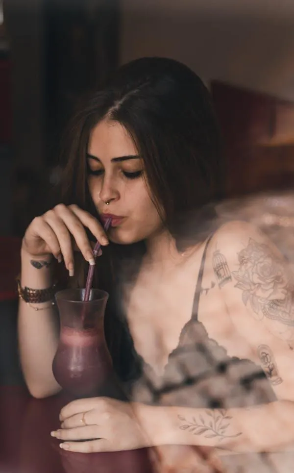 Stylish Woman Drinking From a Glass in a Low Light Setting