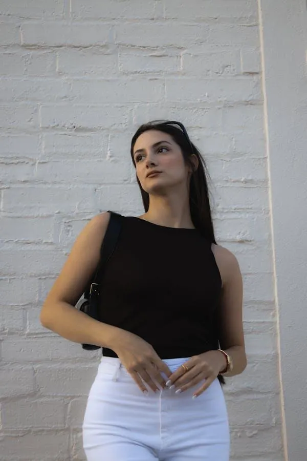 Stylish Woman Leaning Against a White Brick Wall in Sunlight