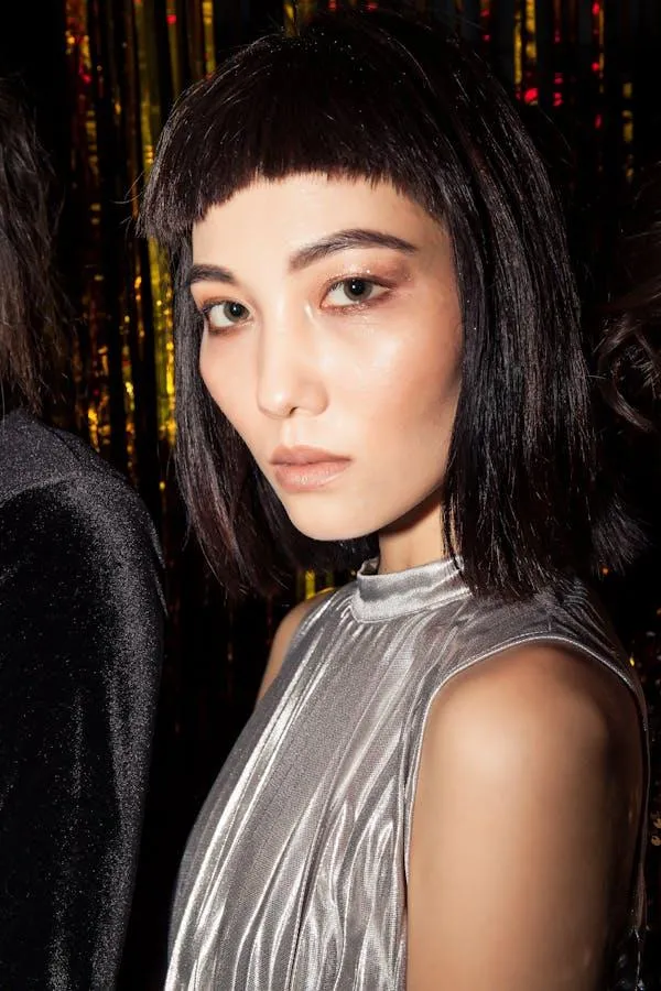 Stylish Woman with Short Bangs Posing in a Silver Outfit