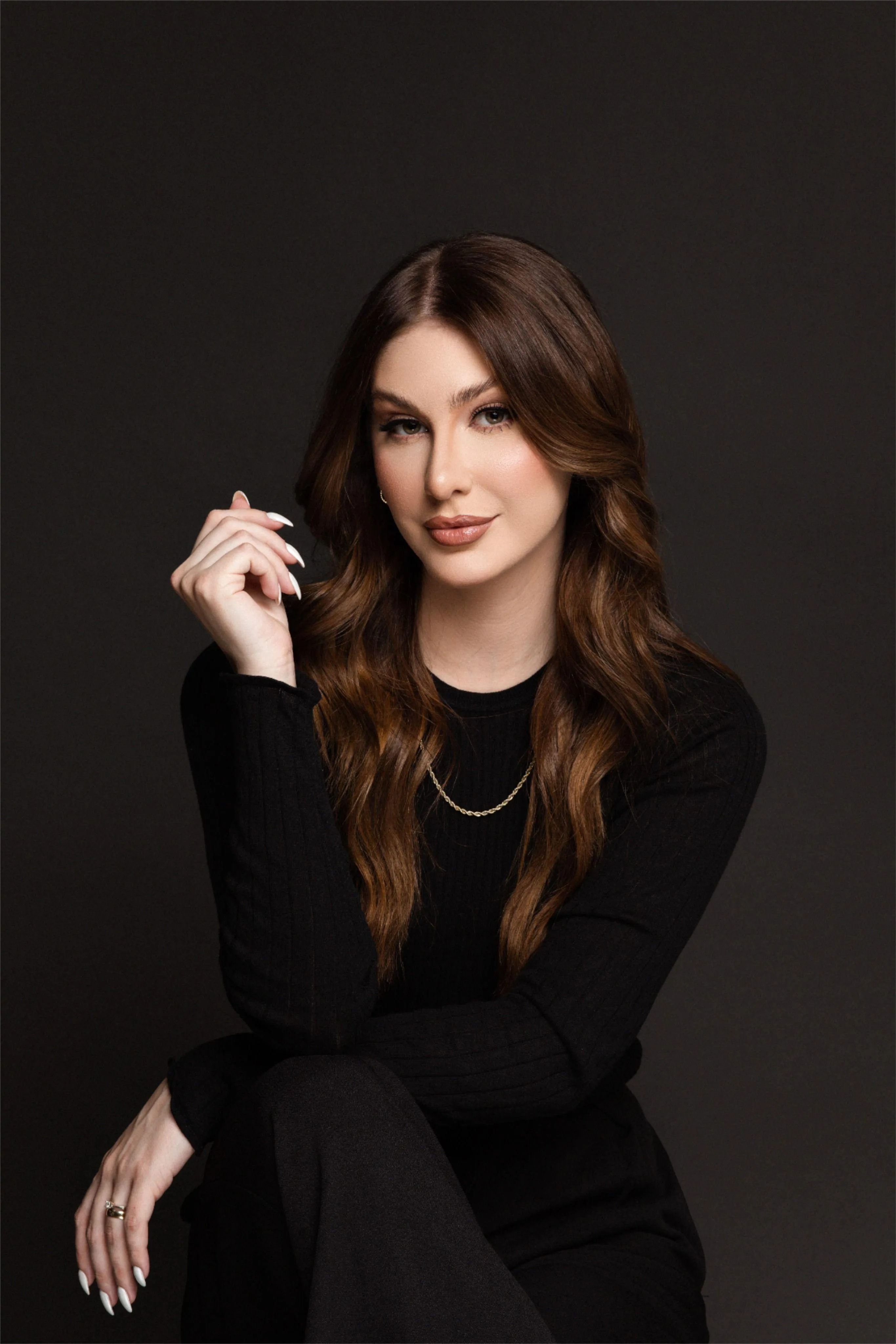 Stylish Woman Sitting Against a Dark Background in Black