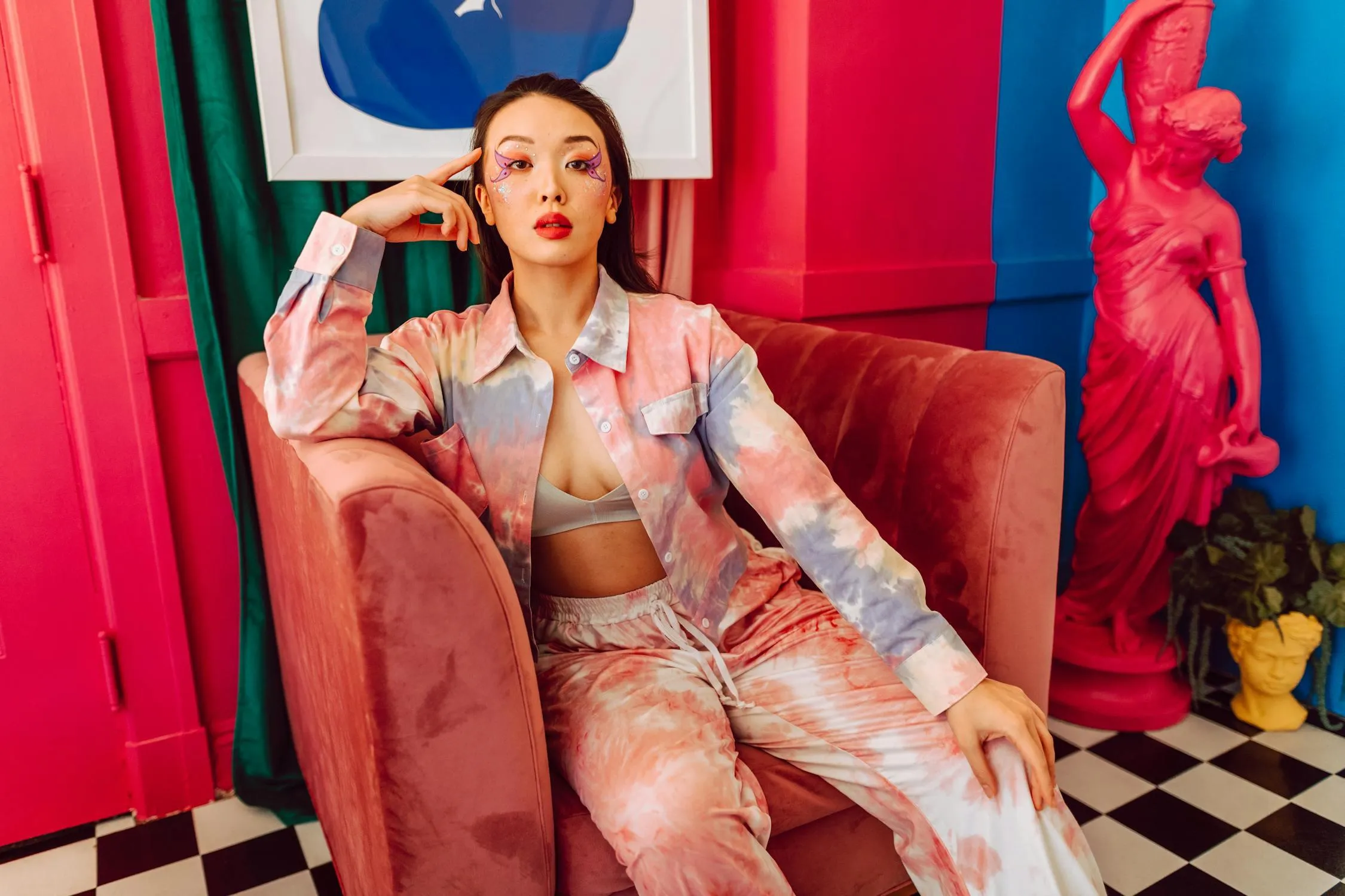 Stylish Woman Sitting on a Pink Chair in Colorful Fashion