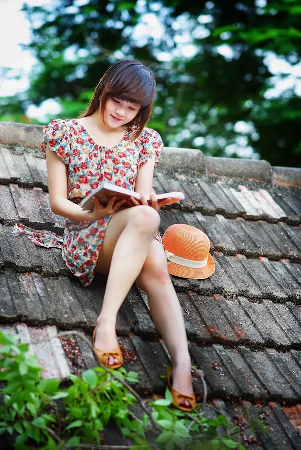 Stylish Woman Sitting on a Rooftop Reading with Orange Hat