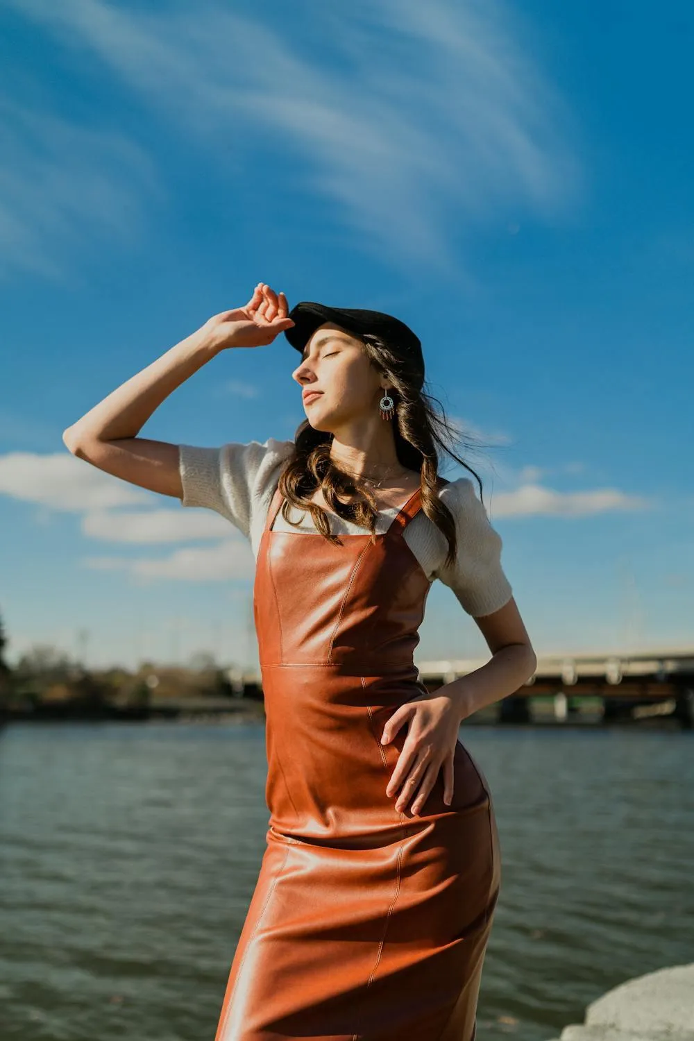 Stylish Woman in a Sleeveless Dress Posing Under a Blue Sky