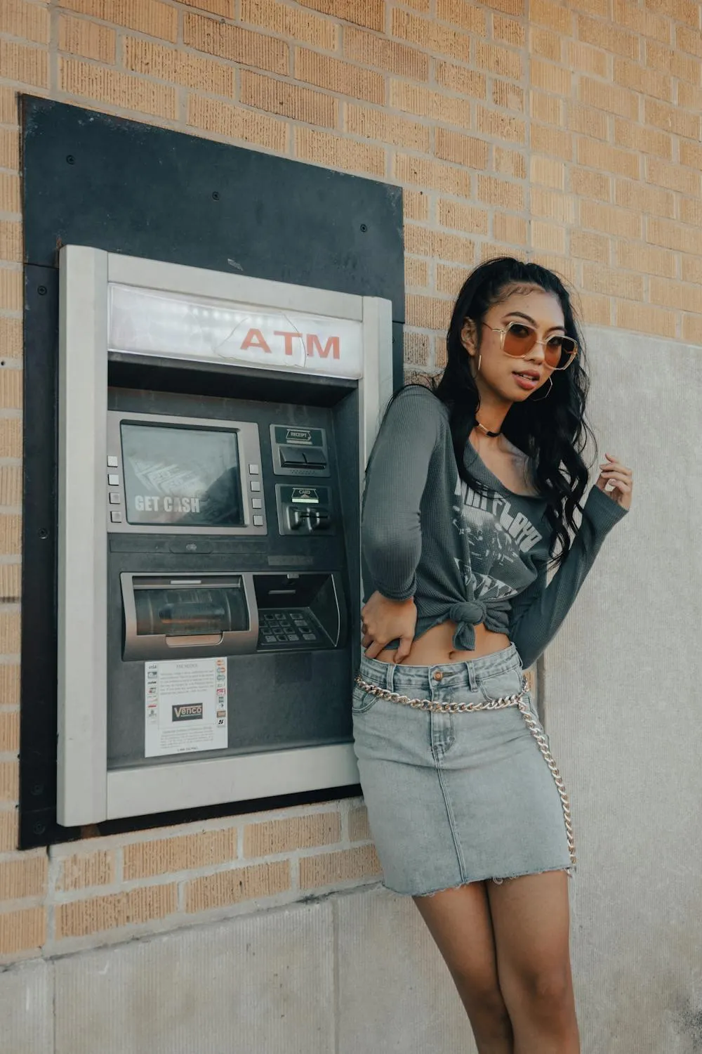 Stylish Woman Standing Near Atm in a Denim Jacket and Skirt