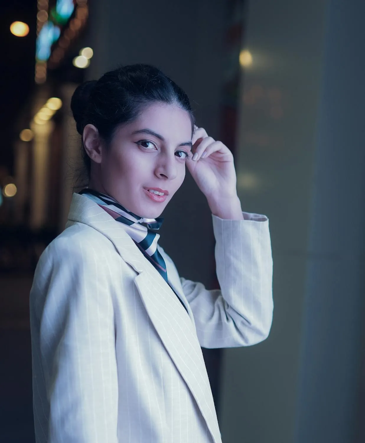 Stylish Woman in a White Blazer Standing Under City Lights