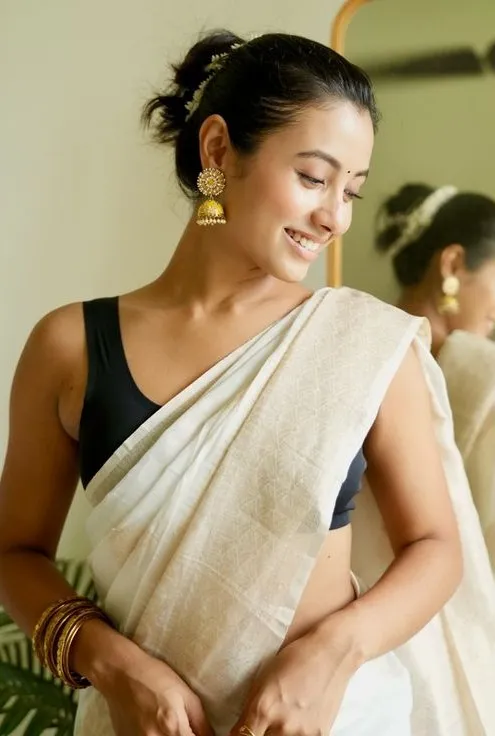 Surabhi Das in a white saree standing near a mirror image