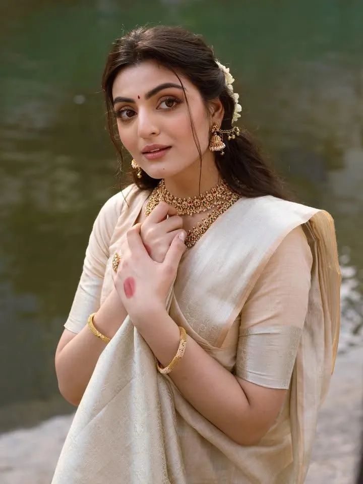 Swati Sharma in a golden saree standing near the water image
