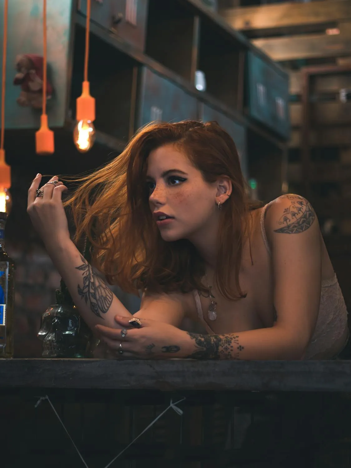 Tattooed Woman Leaning on the Counter with a Moody Lighting