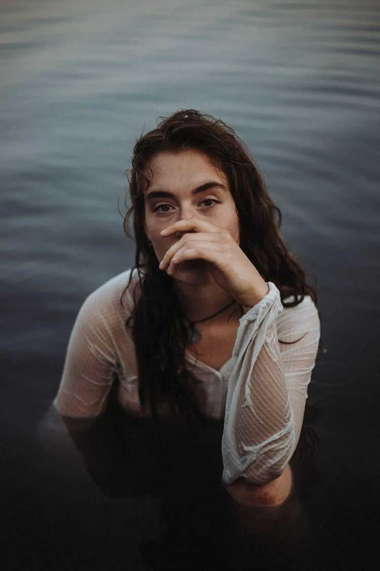Thoughtful Woman Sitting in Water with Her Hand on Chin Pose