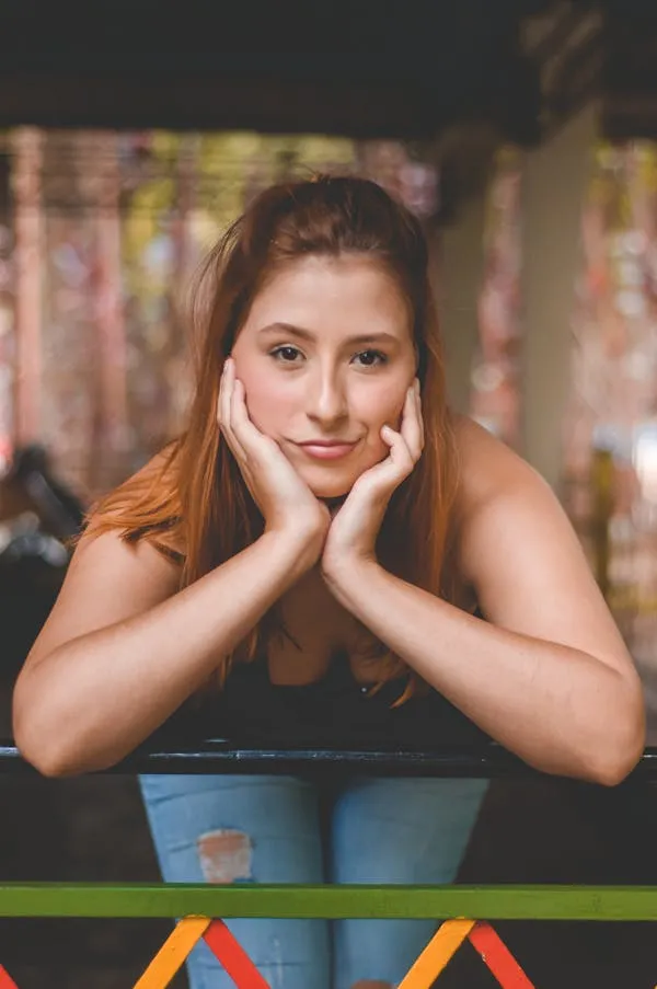Thoughtful Young Woman Resting Arms on a Colorful Table