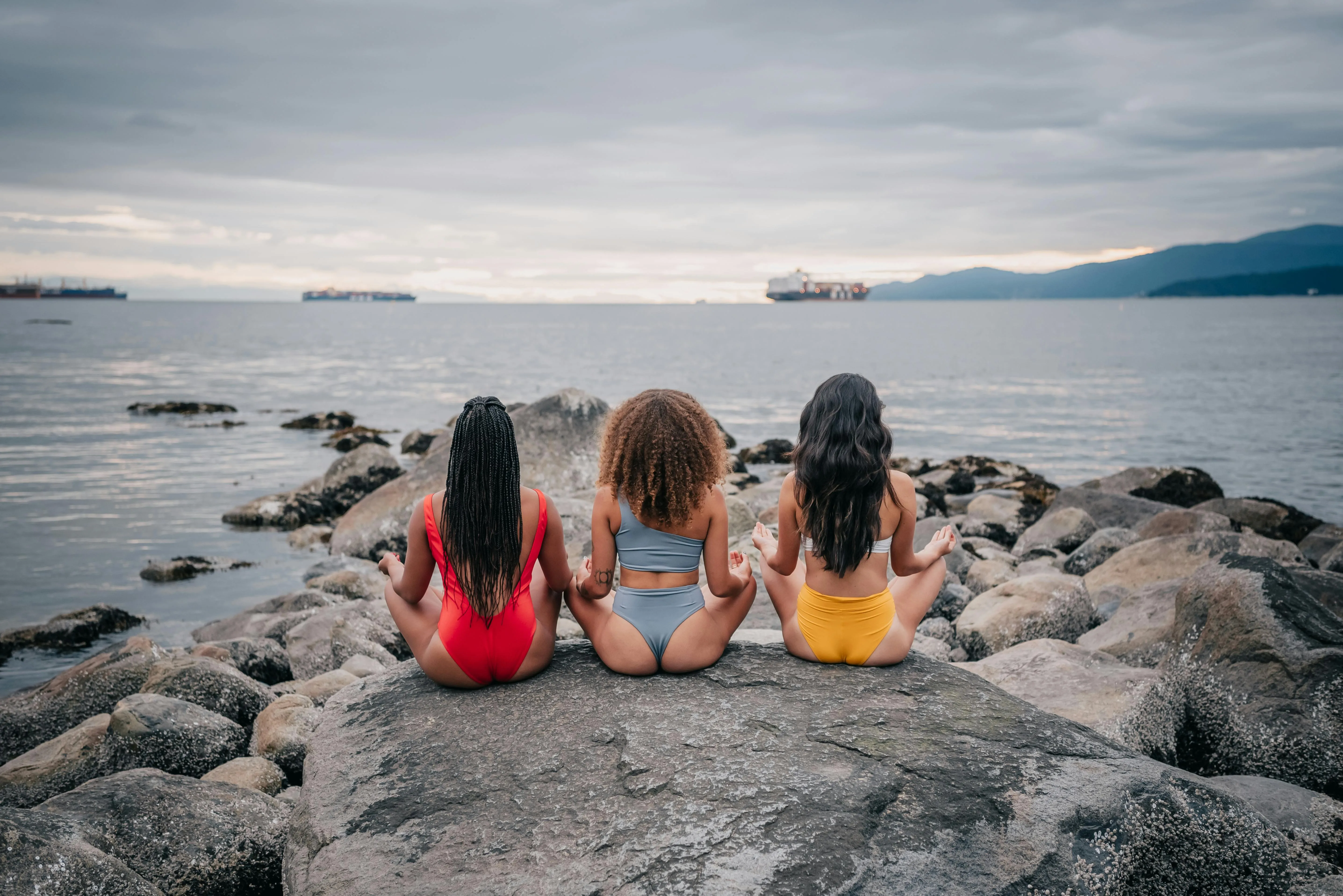 Three Women Sitting on Rocks Looking At the Sea Horizon