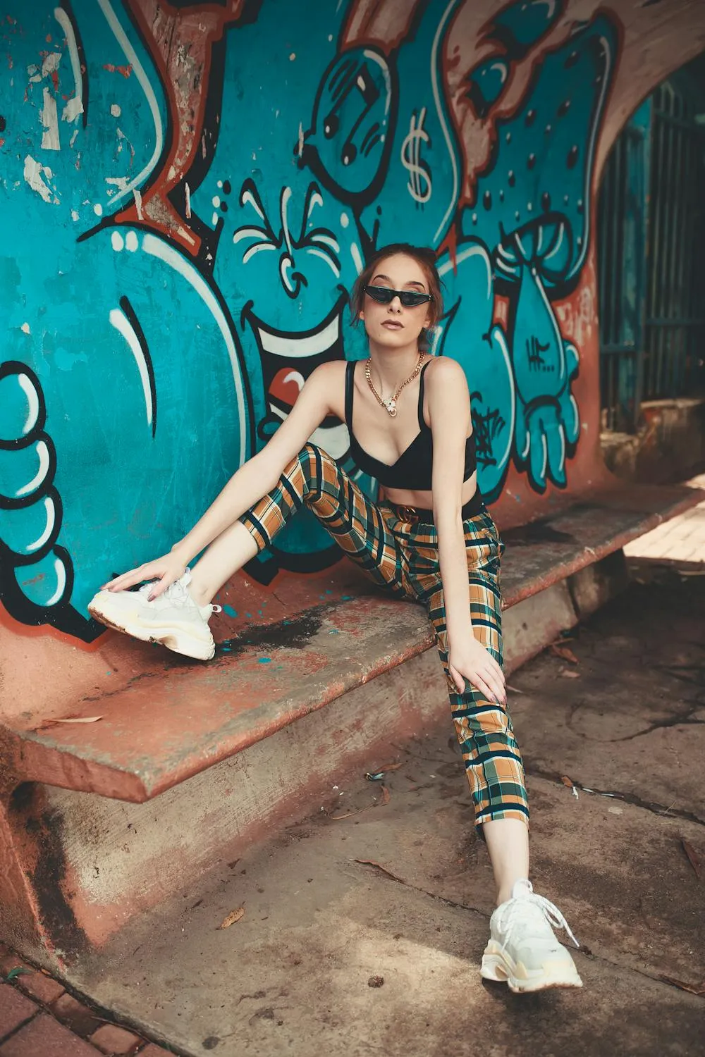 Trendy Woman Posing on Steps Near a Graffiti Wall Wallpaper