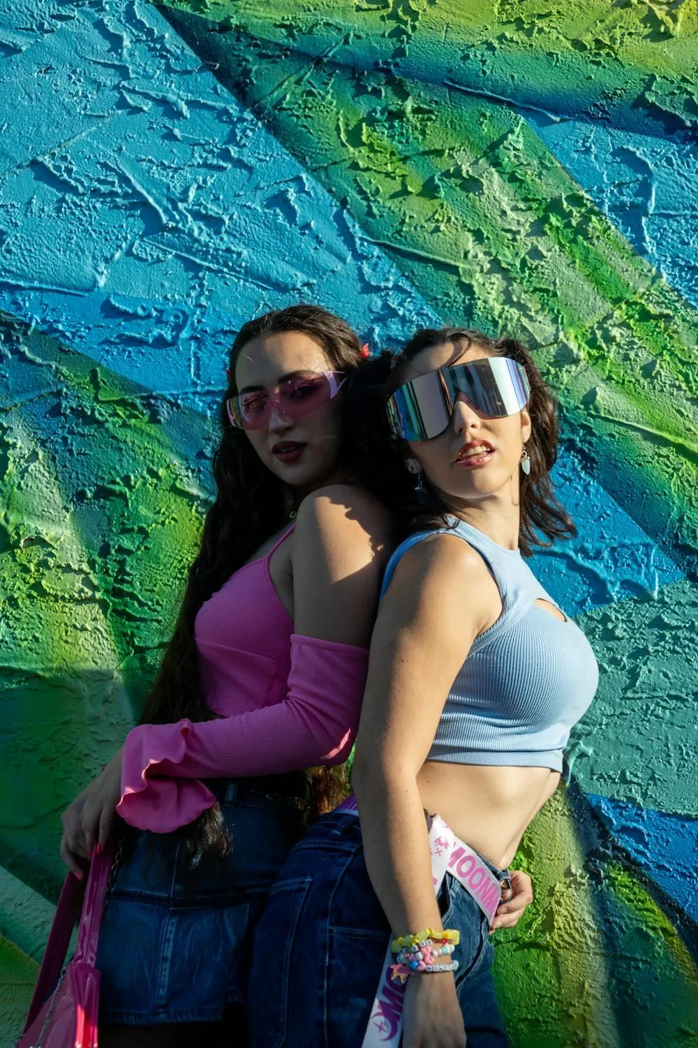 Two Women in a Bold Outfits Posing Near a Graffiti Wall