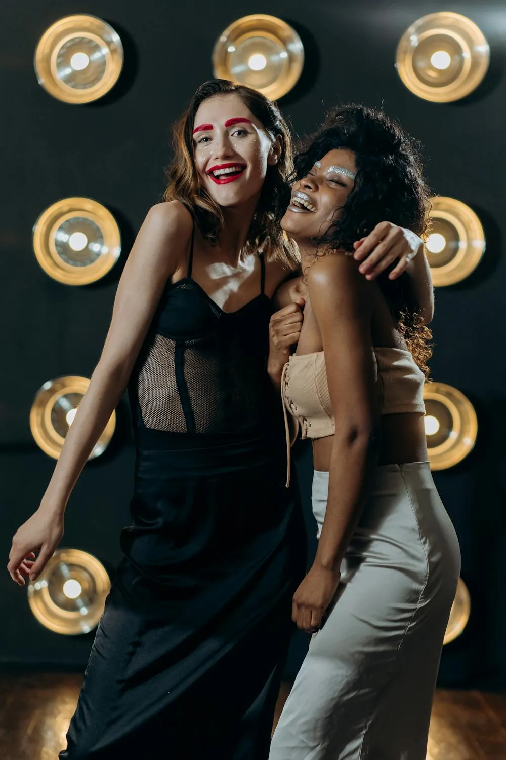 Two Women Smiling and Posing in Front of a Light Bulb