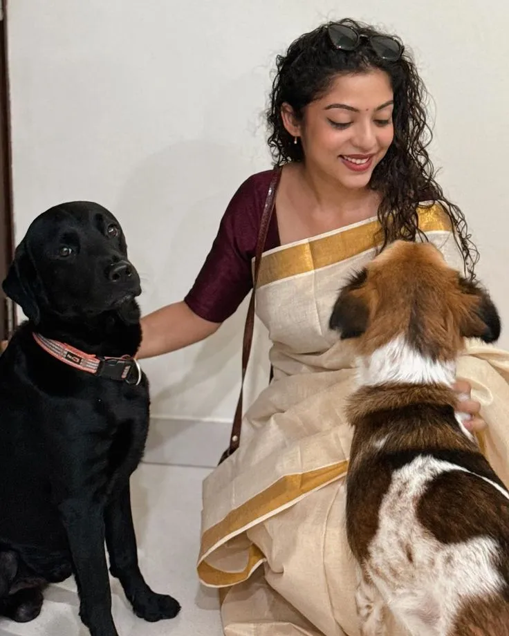 Varsha Bollamma in an Onam saree with her puppy Hachiko