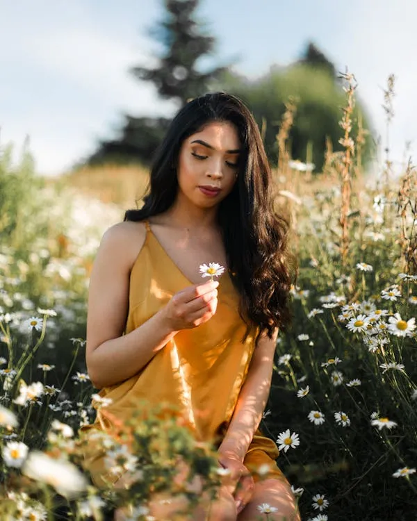 Woman in an Orange Dress Standing in a Sunny Flower Field