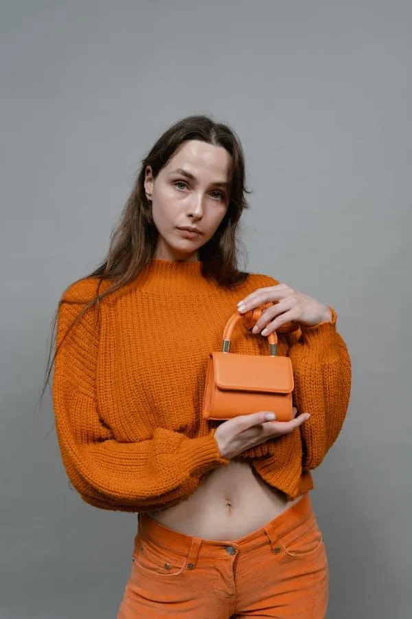 Woman in an Orange Sweater Holding Matching Purse and Posing