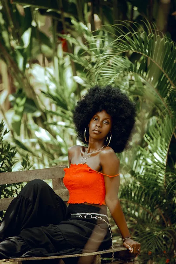 Woman in an Orange Top Surrounded by Lush Tropical Plants