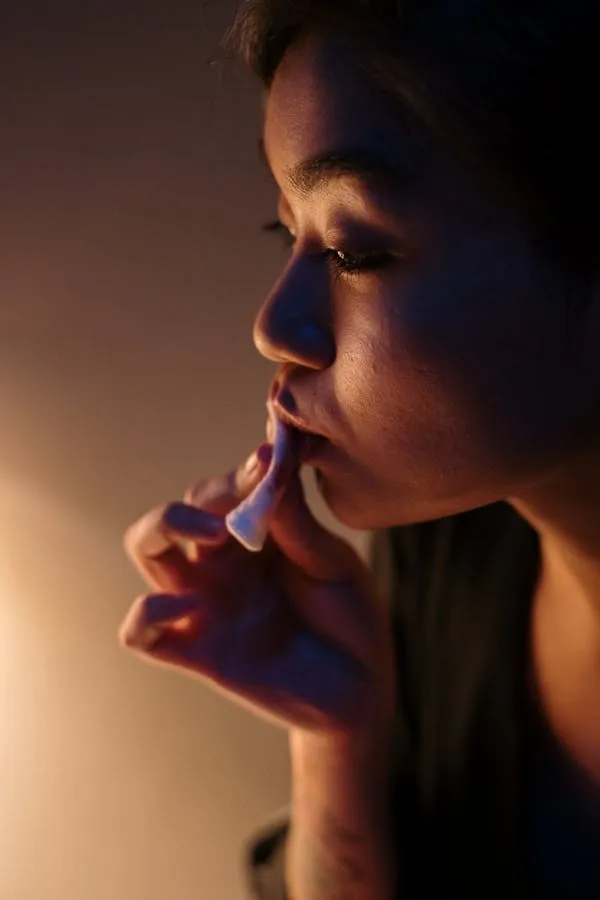 Woman Applying Lipstick in a Dimly Light Warm Atmosphere