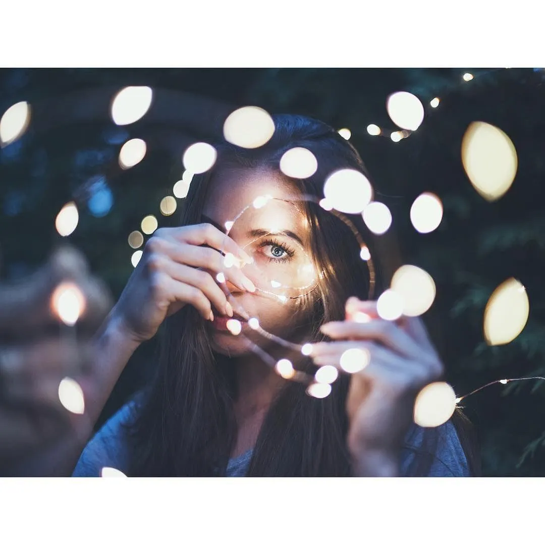 Woman Behind String Lights Creating a Dreamy Bokeh Effect