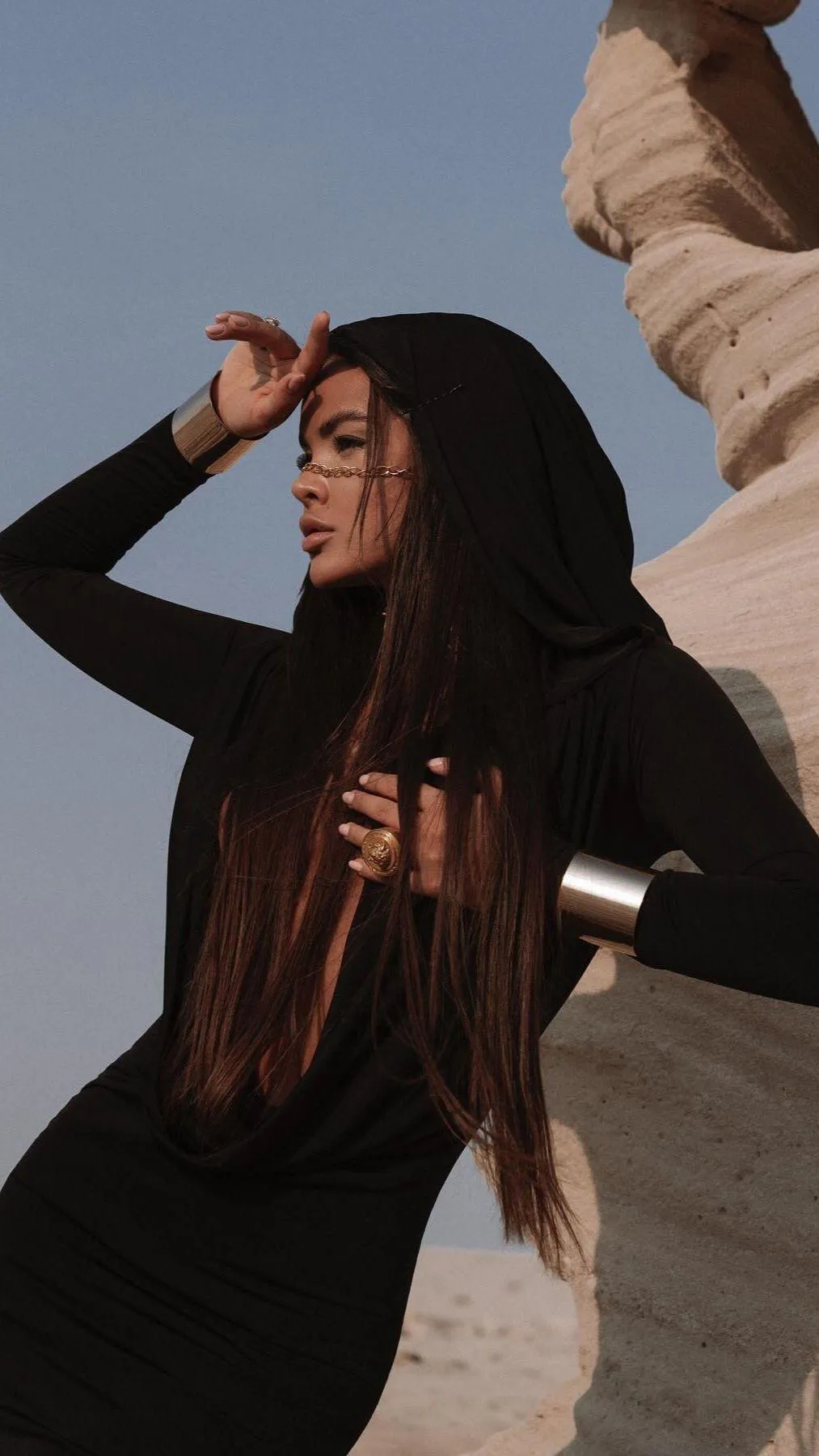 Woman in a Black Dress Posing with Hand on Forehead Outdoors