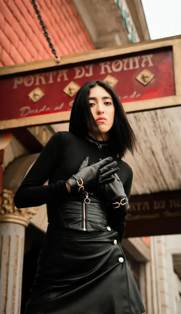 Woman in a Black Dress Posing Near the Red Building Exterior