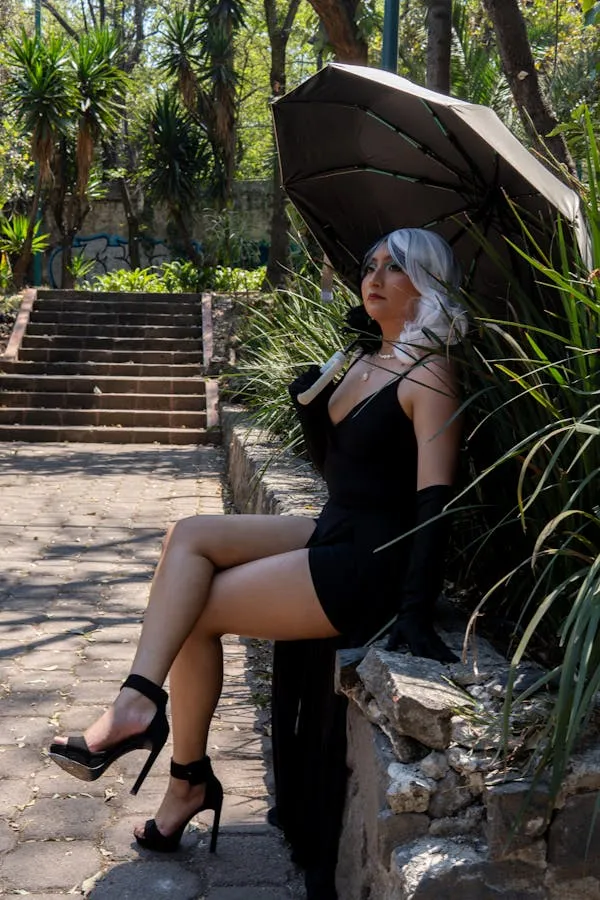 Woman in a Black Dress Sitting on Stone Stairs Outdoors