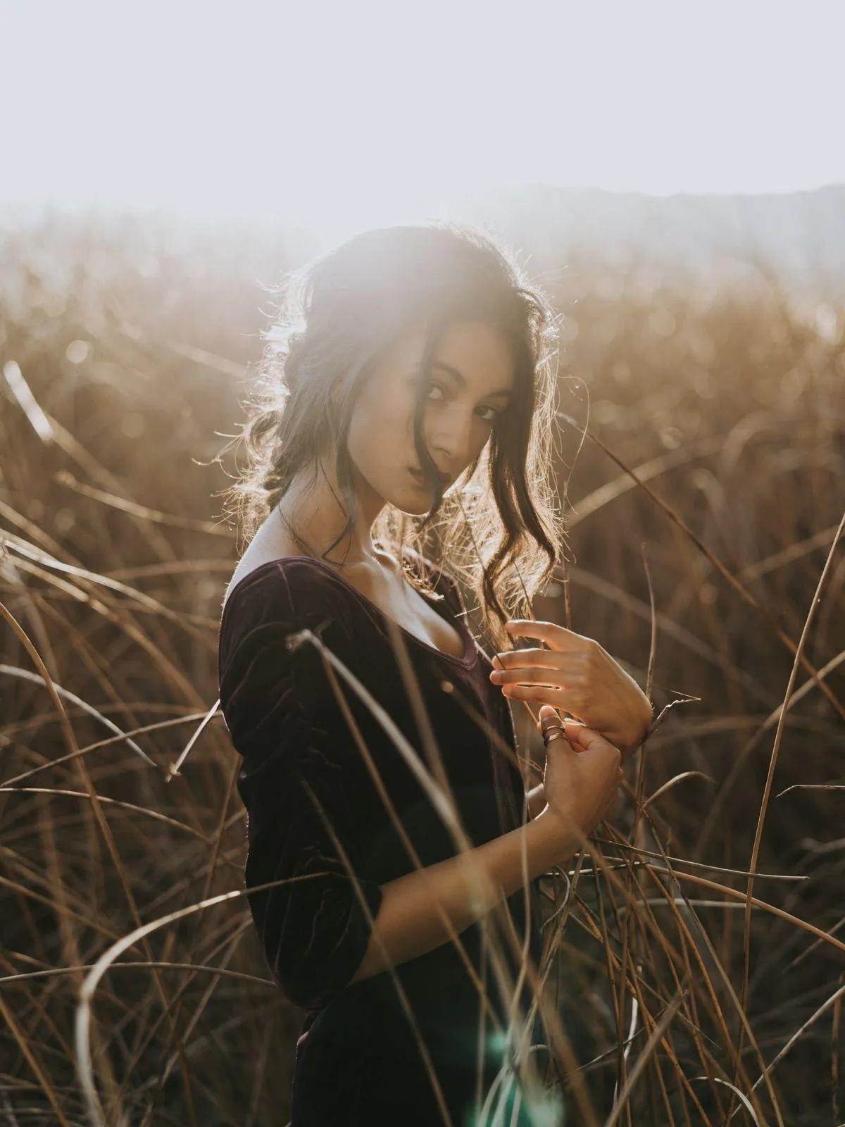 Woman in a Black Dress Standing in Tall Dry Grass Outdoors