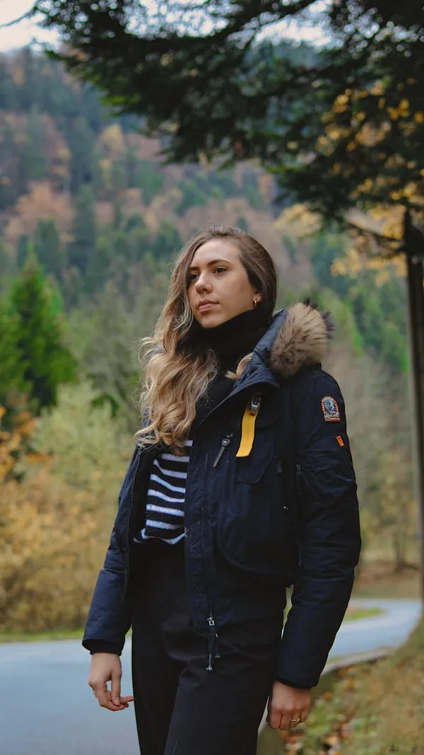 Woman with a Black Jacket Standing Outdoors in a Forest