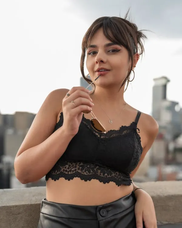 Woman in a Black Lace Crop Top Smiling on a City Rooftop