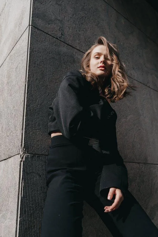 Woman in a Black Outfit Leaning on the Stone Wall Wallpaper