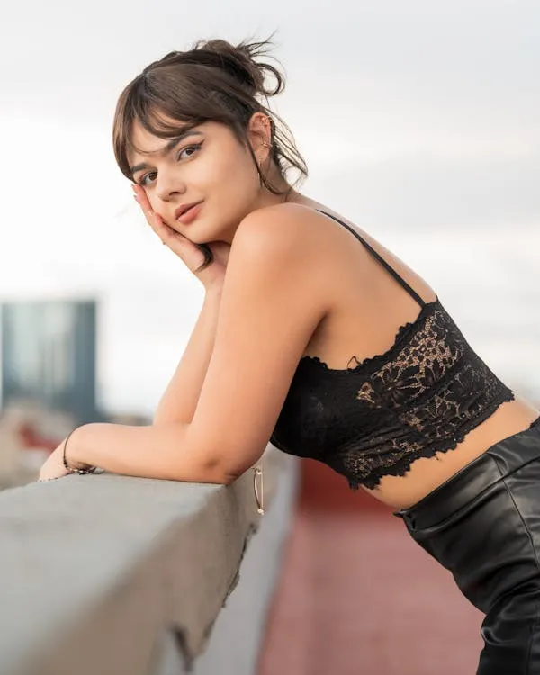 Woman in Black Top Leaning on a Balcony in City View Image