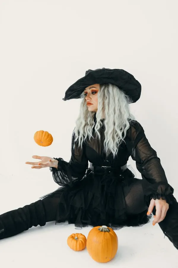 Woman in a Black Witch Costume with Silver Hair and Pumpkins