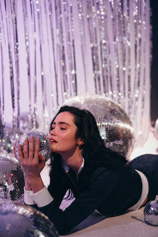 Woman Blowing Glitter At a Party in Front of Shiny Backdrop