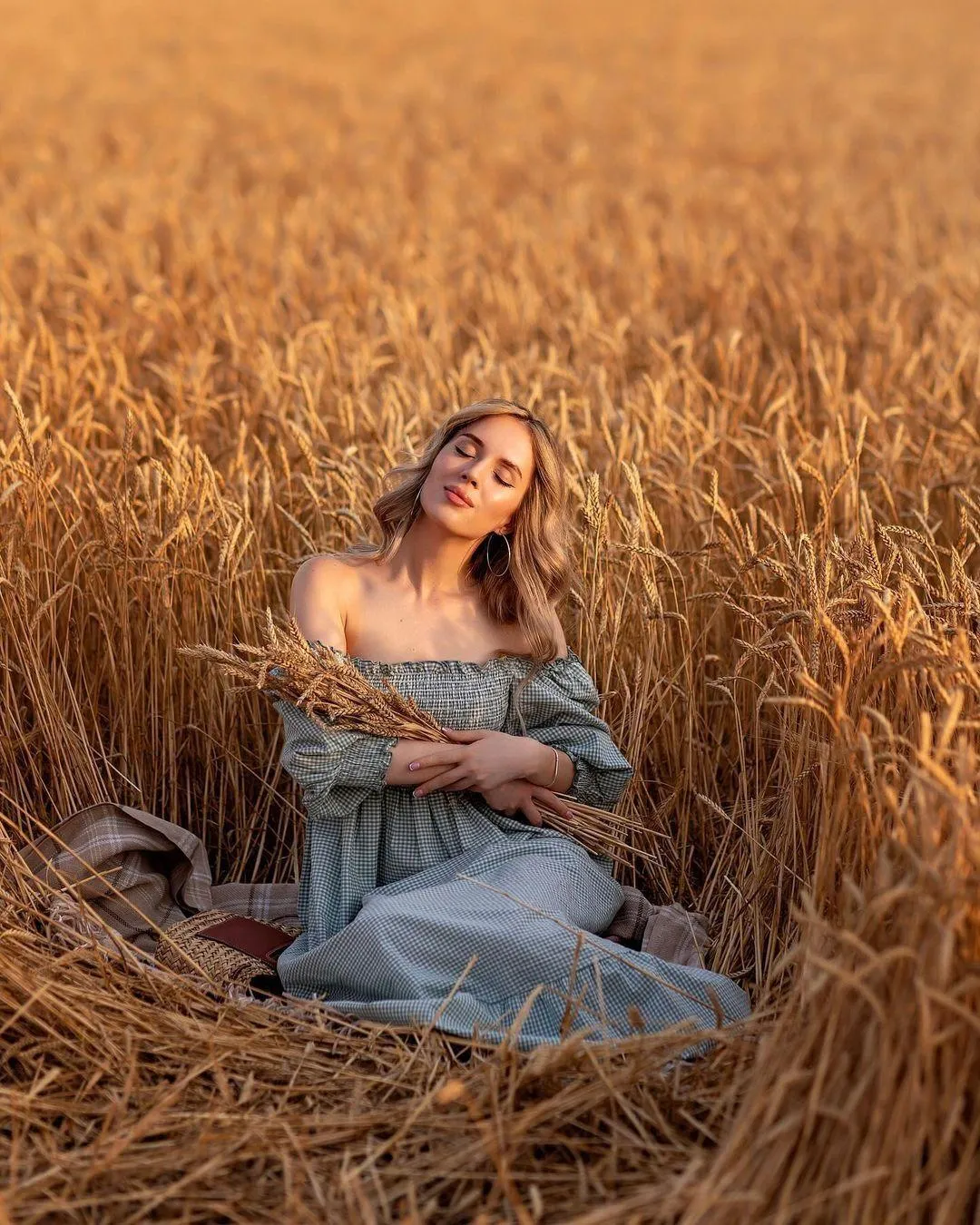 Woman in a Blue Dress Seated Peacefully in a Wheat Field