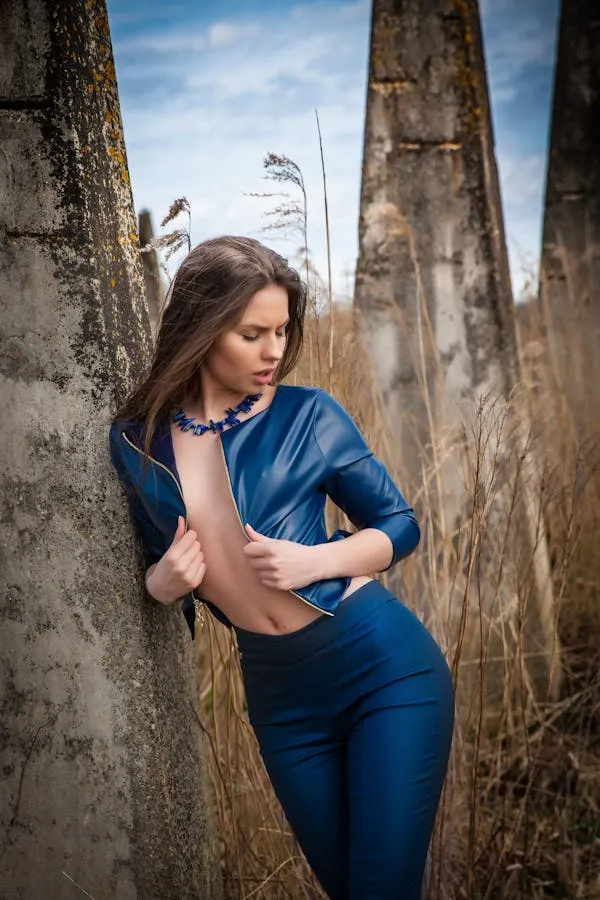 Woman in a Blue Outfit Posing Beside Ancient Stone Pillars