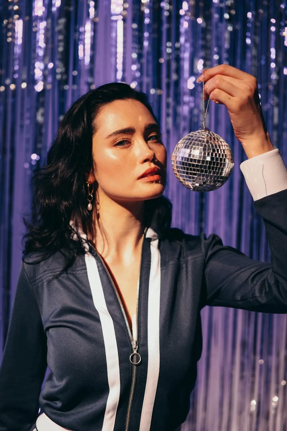 Woman in a Blue Suit Holding Disco Ball with Purple Backdrop