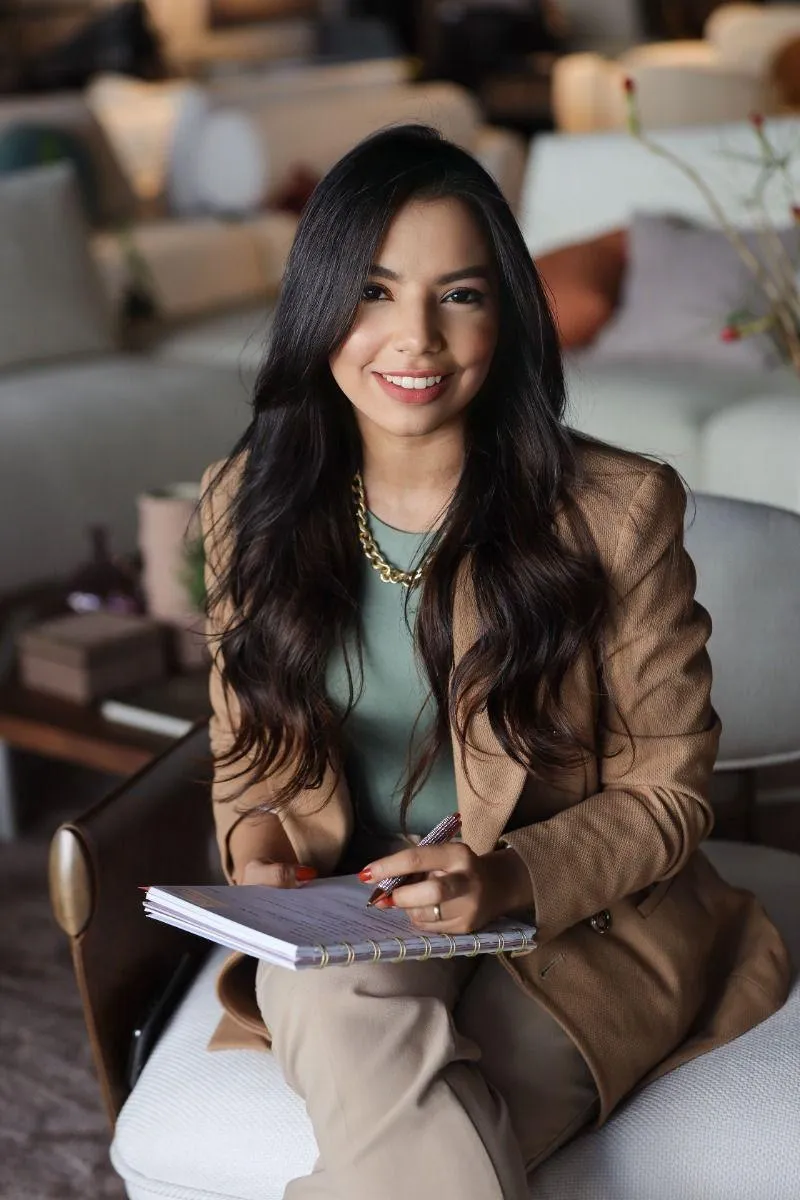 Woman in a Brown Blazer Sitting with a Notebook and Smiling