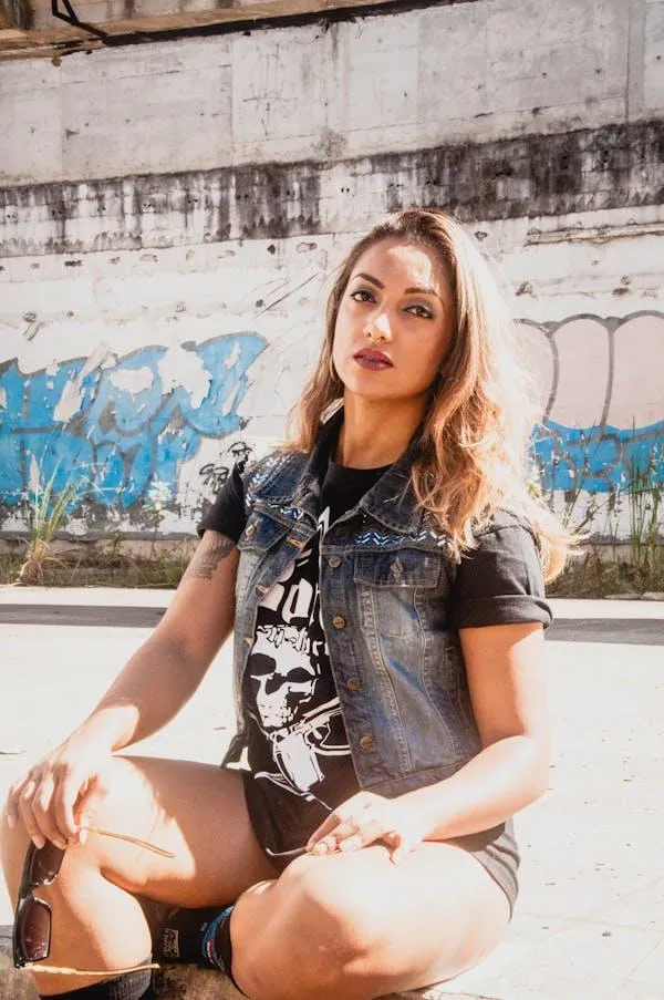 Woman with Casual Outfit Sitting Outdoors Near Graffiti Wall