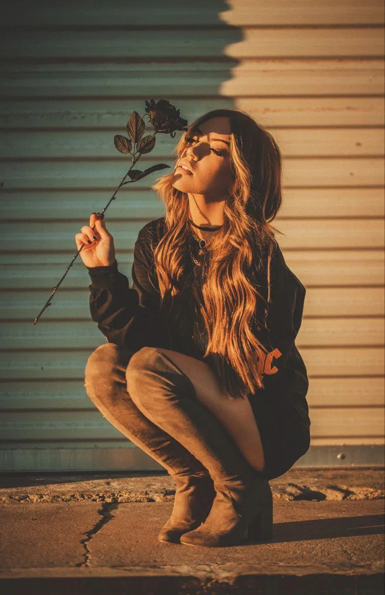 Woman Crouching in Golden Sunlight Near a Corrugated Wall